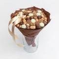 Small gift in the form of a bouquet of chocolates is in a vase on a white background