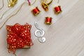 Small gift present box with colorful ribbon bow tie placed on wooden table with small decorative music instruments on Christmas