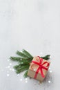 A small gift wrapped in kraft paper with a red ribbon on a light blue background with natural Christmas tree branches Royalty Free Stock Photo