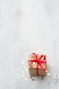 A small gift wrapped in kraft paper with a red ribbon on a light blue background, surrounded by a shiny confetti star Royalty Free Stock Photo