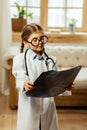 Small girl in adult glasses examining the x-ray in hands.