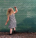 Small girl banging on a green fence