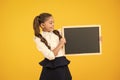 Small girl, big dream. Small child holding black-board for school advertisement on yellow background. Small kid with