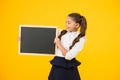 Small girl, big dream. Small child holding black-board for school advertisement on yellow background. Small kid with