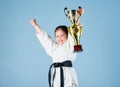 Small girl with champion cup. martial arts. winner little girl in gi sportswear. practicing Kung Fu. childhood. knockout