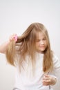 small girl combs long and tangled hair. white background.