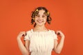 Small girl Curling Hair Using Curlers orange background. Hairdresser salon. Female beauty routine. Adorable child hairdo Royalty Free Stock Photo