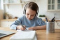 Girl in headphones learning at home doing homework using laptop Royalty Free Stock Photo