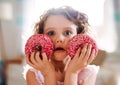 A small girl with doughnuts at home, looking at camera. Royalty Free Stock Photo