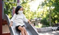 Small girl with face mask on slide outdoors in town, coronavirus concept. Royalty Free Stock Photo