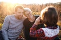 Small girl with family on picnic in autumn nature, taking photographs with camera. Royalty Free Stock Photo