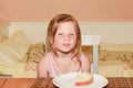 Small girl has a snack. Little girl eats bread spread with cheese. Cute girl in kitchen. Family and childhood concept.