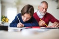 A small girl and her grandfather writing Christmas cards together. Royalty Free Stock Photo