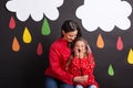 A small girl with her mother on a black background with clouds and raindrops.