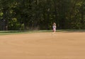 Small girl kicking up dust on a smoothly raked baseball infield