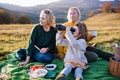 Small girl with mother and grandmother having picnic in nature, using binoculars.