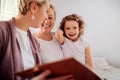 A small girl with mother and grandmother at home, looking at photographs. Royalty Free Stock Photo
