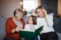 A small girl with mother and grandmother at home. Royalty Free Stock Photo