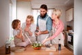 A small girl with parents and grandmother at home, preparing vegetable salad.