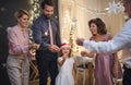 Small girl with parents and grandparents indoors celebrating Christmas.