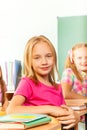 Small girl in pink tshirt sits at desk and looks Royalty Free Stock Photo