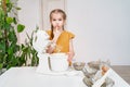small girl prepares dough or cream in a submersible mixer and licks his fingers