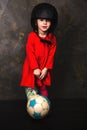 Small girl in a red dress and helmet with ball in studio Royalty Free Stock Photo