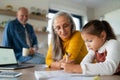 Small girl with senior grandparents doing maths homework at home. Royalty Free Stock Photo