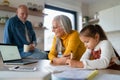 Small girl with senior grandparents doing maths homework at home. Royalty Free Stock Photo