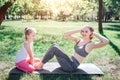 Small girl is sitting on carimate and holding feet of her mom while woman is doing some abs excercises. She is kepping