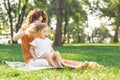 Small girl sitting on mother legs while she doing her hair in the park Royalty Free Stock Photo