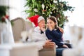 A small girl telling a secret to her grandfather with Santa hat at Christmas time. Royalty Free Stock Photo