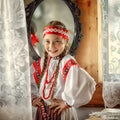 A small girl in a traditional Russian costume on the background of a mirror
