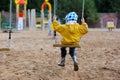 Small girl in yellow rain coat on swing