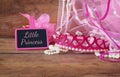 Small girls party outfit: crown and wand flowers next to small chalkboard with phrase LITTLE PRINCESS: on wooden table