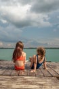 Small girls sitting on the lake wooden pier Royalty Free Stock Photo