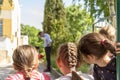 Small girls are watching a performance of a magician through an outdoor birthday party