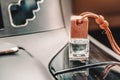 Small glass bottle with car perfume on the black car dashboard