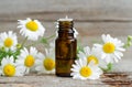 Small glass bottle with essential roman chamomile oil on the old wooden background. Aromatherapy, herbal medicine ingredients