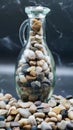 Small glass bottle full of small seashells on rock background