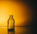 Small glass bottle in the shade, lit from the side on a yellow background Royalty Free Stock Photo