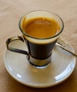 Small glass cup of black arabica coffee served in cafe, close up