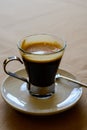 Small glass cup of black arabica coffee served in cafe, close up