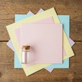 A small glass jar with a cork lid is placed on a stack of pastel-colored square papers Royalty Free Stock Photo