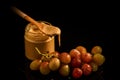 Small glass jar with creamy peanut butter next to purple grapes