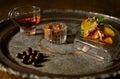 Small glass with liquor, nuts in a glass pot, peaches in syrup in small glass tray on a metal tray on a table. Royalty Free Stock Photo