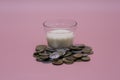 small glass of milk with coins around