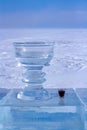 A small glass with red liquor and a large ice cup stand against a background of white snow. Royalty Free Stock Photo