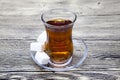 A small glass of Turkish tea, a plate of sugar on a wooden table. Can be used as photos for the menu of the Eastern Turkish confec