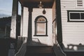 small glass window by the entrance stairs of a cute little old wooden house in a quiet village at sunset, west Royalty Free Stock Photo